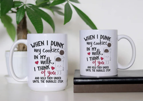 Dunking Delights white ceramic coffee mug featuring cute cookies, a smiling glass of milk, red hearts and the funny “When I dunk my cookies in my milk, I think of you” dark-humor design, available in 11 oz and 15 oz sizes.